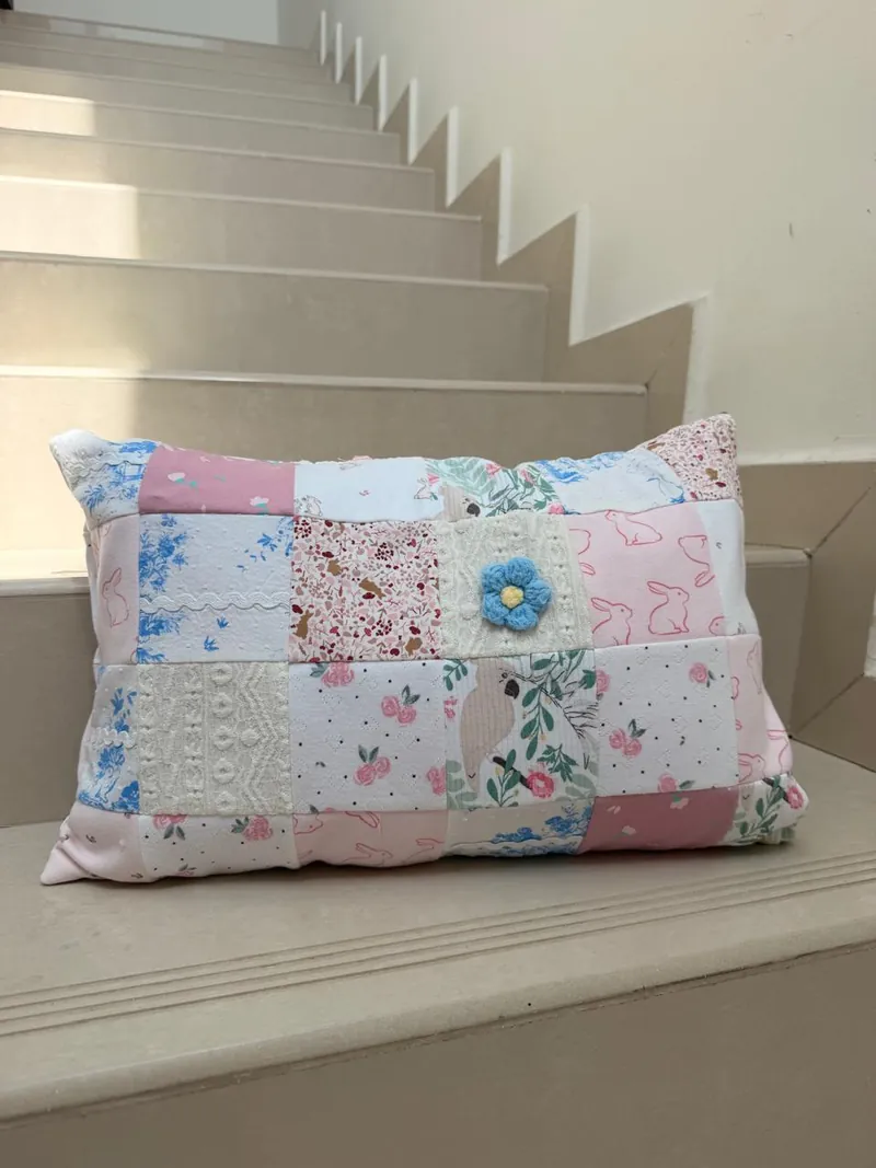 Pink patchwork cushion made from baby clothes, resting on a stair