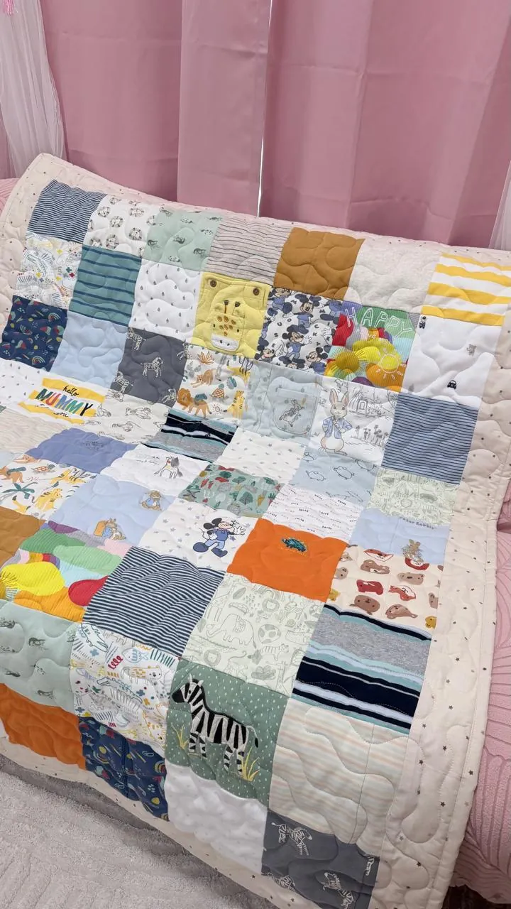 Baby clothes memory quilt by Andi, draped over a chair