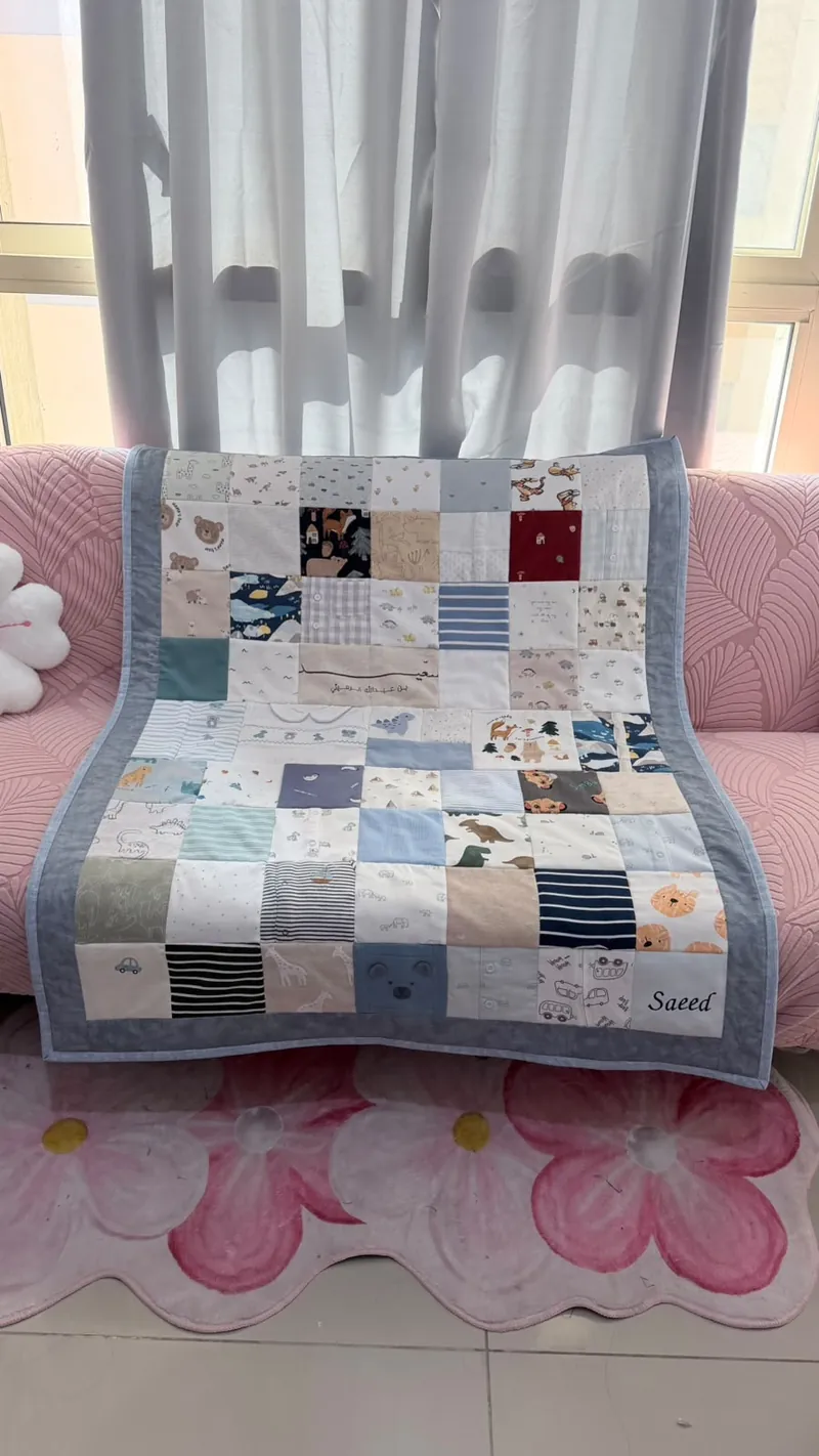 Blue-bordered baby clothes memory quilt embroidered with the name Saeed